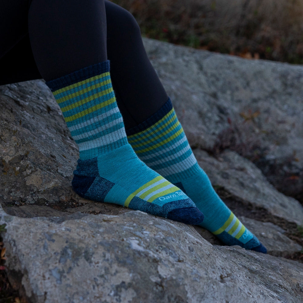 Close-up of a woman's feet on rocks wearing aqua striped boot socks