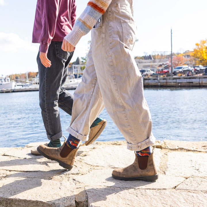 Woman walking on stone near water wearing boots with women&