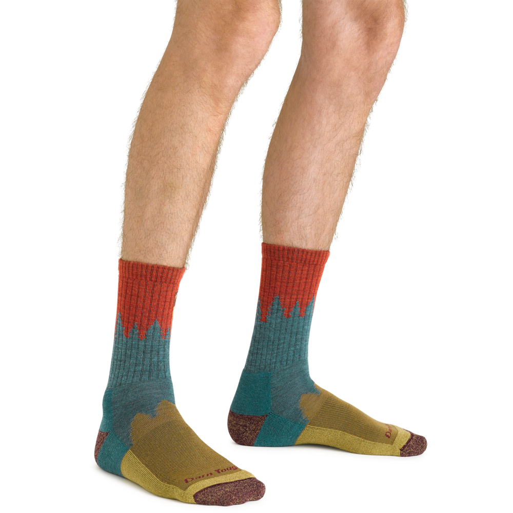 Men's teal forest-scene hiking socks worn on legs, front view above the ankle