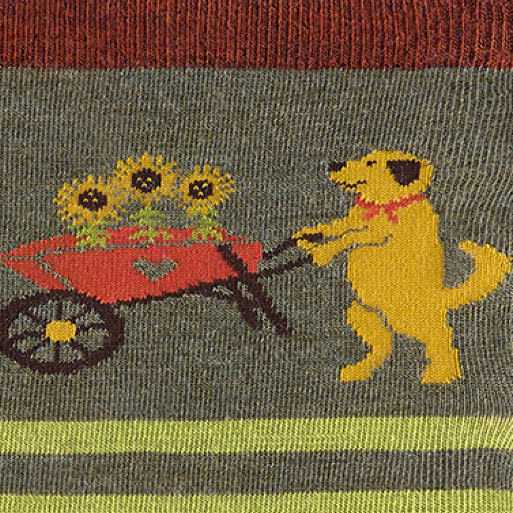 Close-up of the knitted dog pushing a sunflower wheelbarrow on the green sock