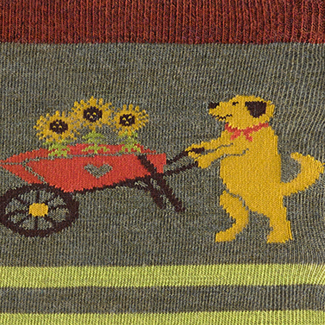 Close-up of the knitted dog pushing a sunflower wheelbarrow on the green sock