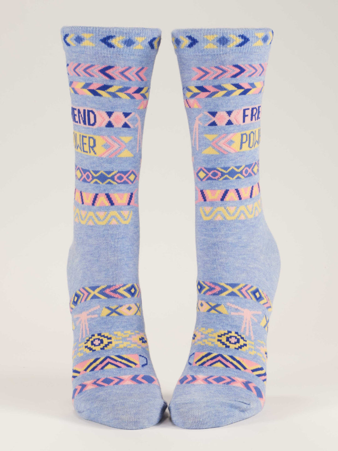 The Blue Q Friend Power W-Crew Socks are sustainable blue combed cotton socks with pink, yellow, and navy geometric patterns and "FRIEND POWER" on the front, displayed upright against a white background.