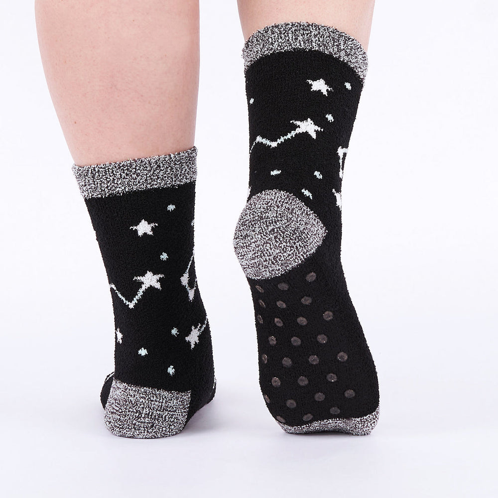 Women's fuzzy moon and stars slipper socks worn, back view with grippy sole dots