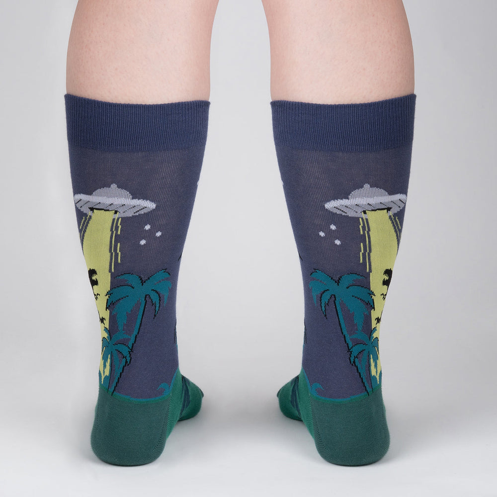 Men's UFO dinosaur crew socks worn, back view with palm trees and tractor beam