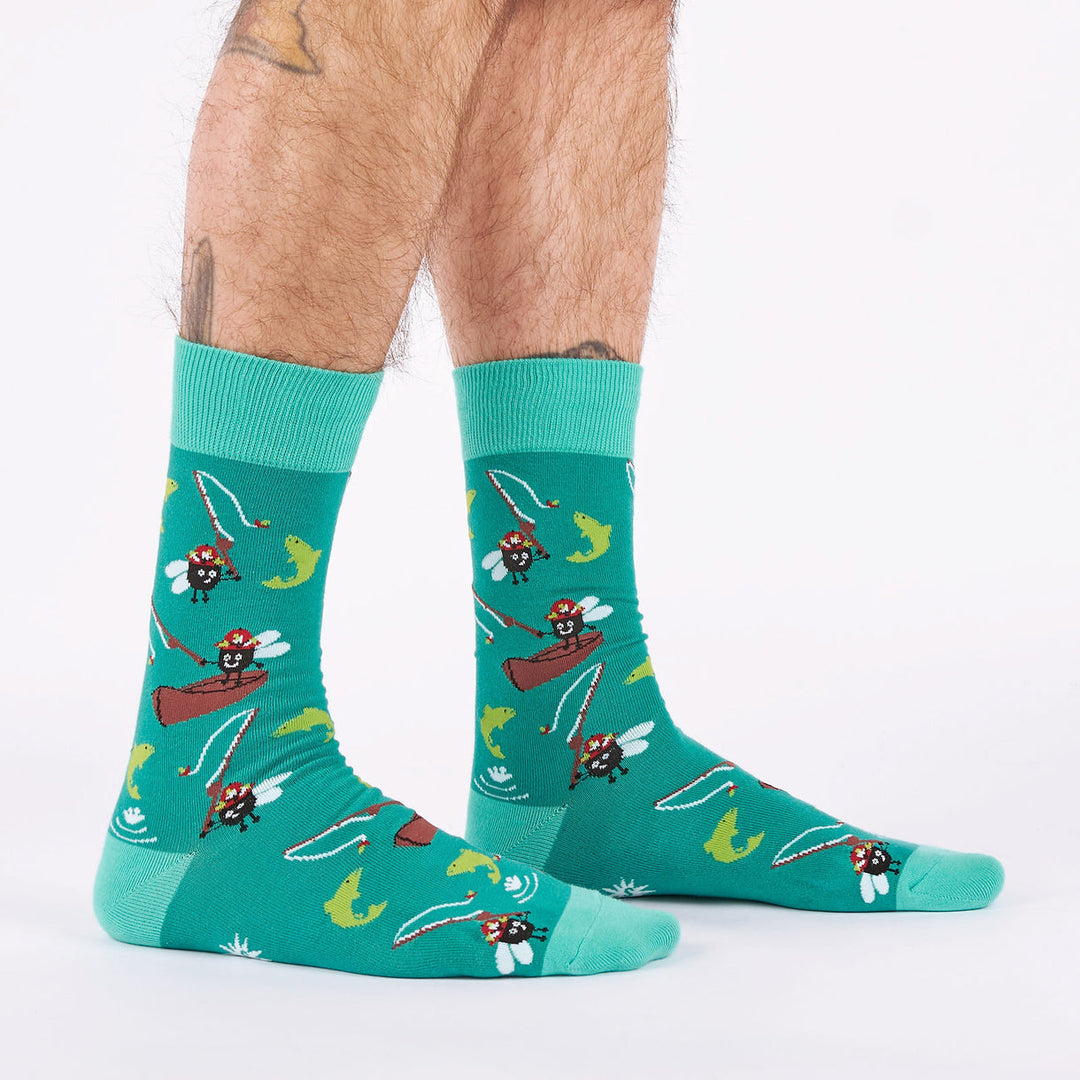 Men's fly fishing crew socks with flies and fish on teal, worn side view