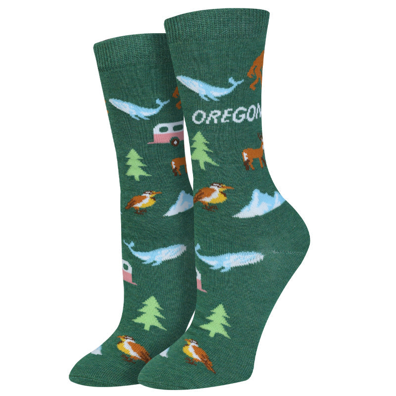 Women's Oregon crew socks, flat pair view with Bigfoot, whales, camper, and trees on green
