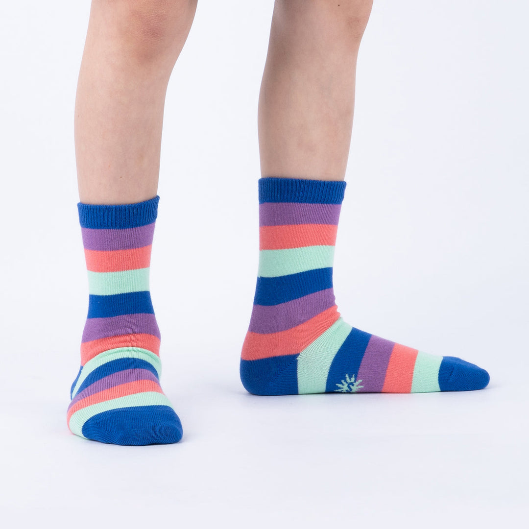 Child wearing rainbow-striped junior crew socks, side view