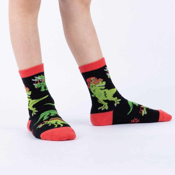 Child wearing black dinosaurs-in-sunglasses junior crew socks, side view