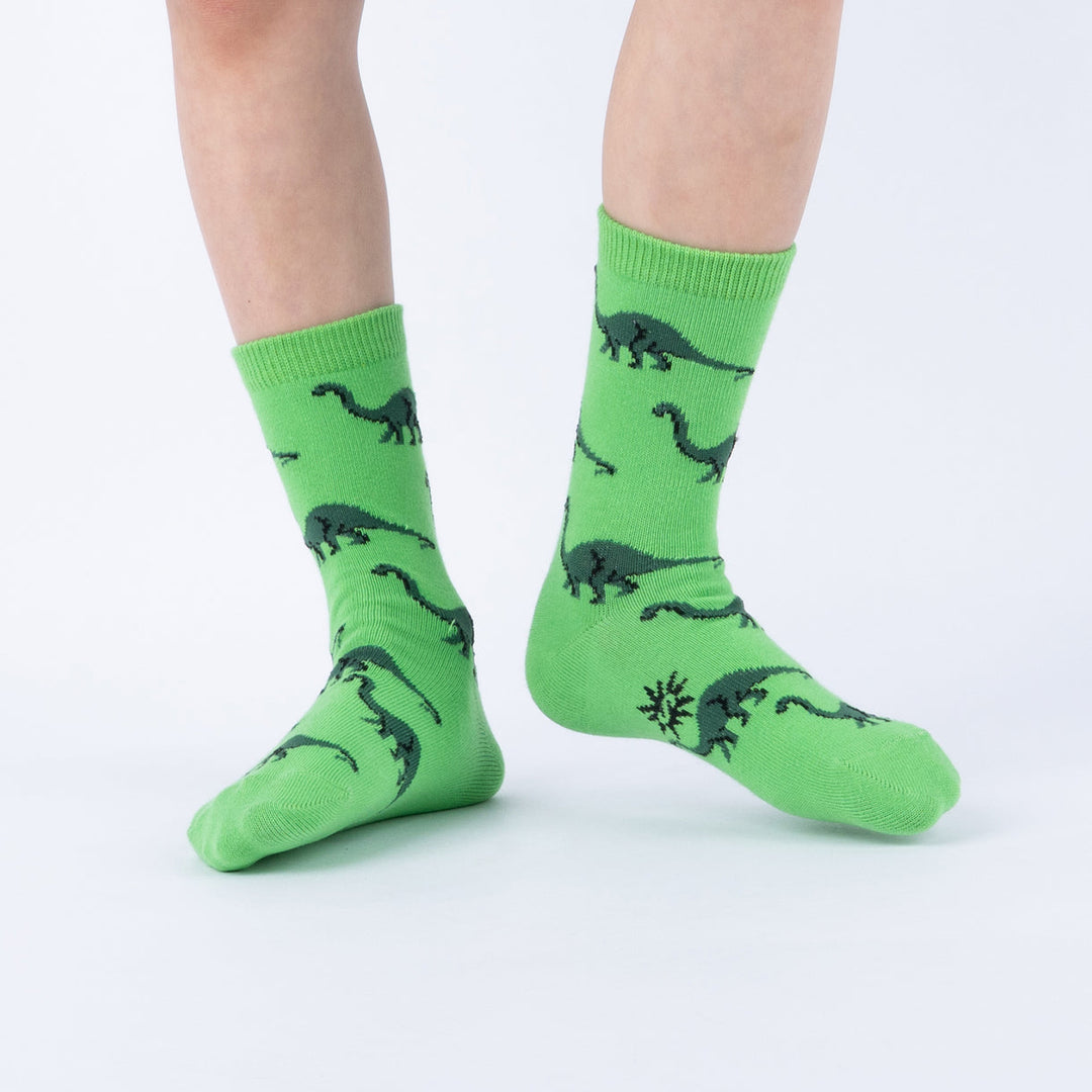 Child wearing green brontosaurus silhouette junior crew socks, front view