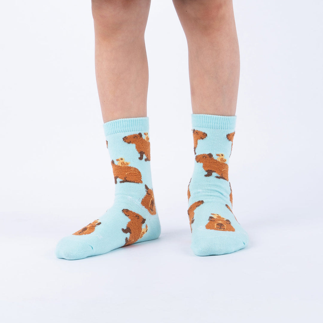 Child wearing mint fuzzy capybara junior crew socks, front view