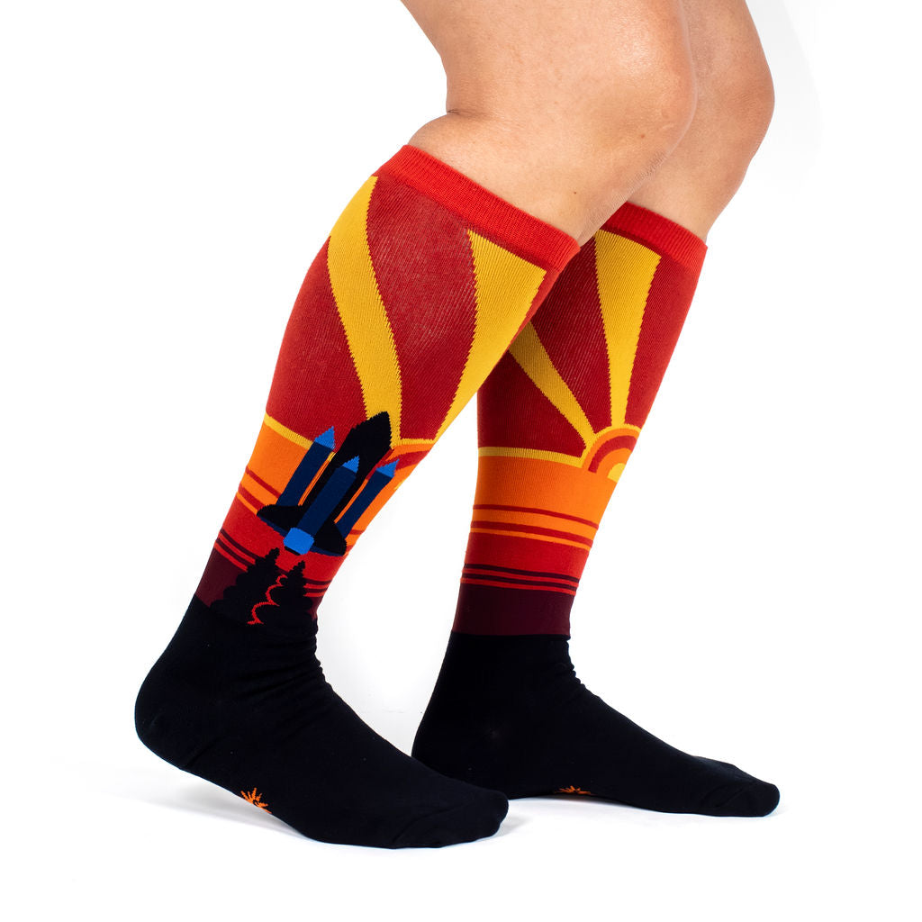 It's Only Rocket Science women's knee high socks with a shuttle launch at sunset, model side view