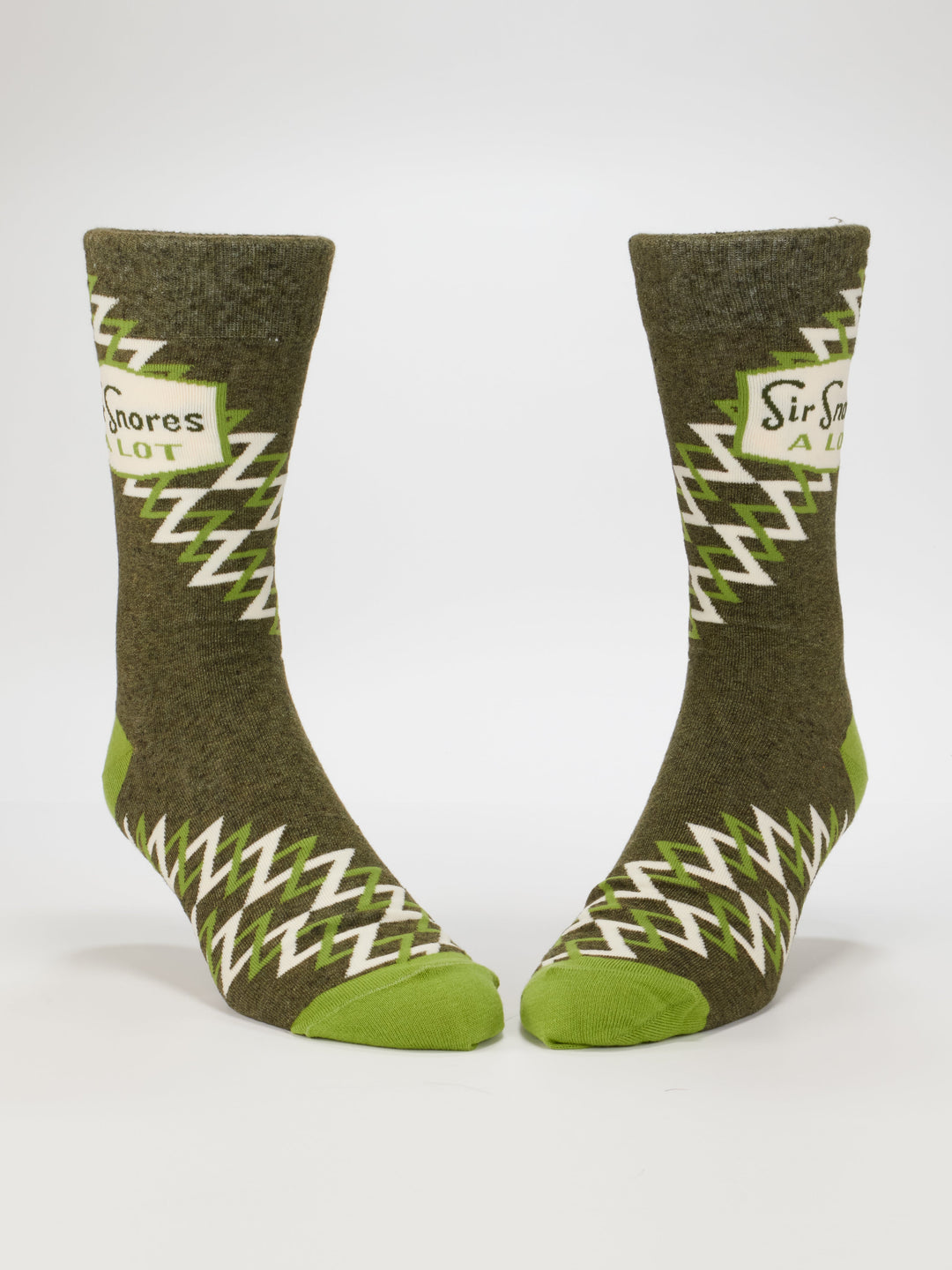 Blue Q Sir Snores A Lot M-Crew Socks, featuring green and brown nylon with zigzag patterns and "Sir Snores A Lot" on the sides, are shown upright against a white background. Fits most men&