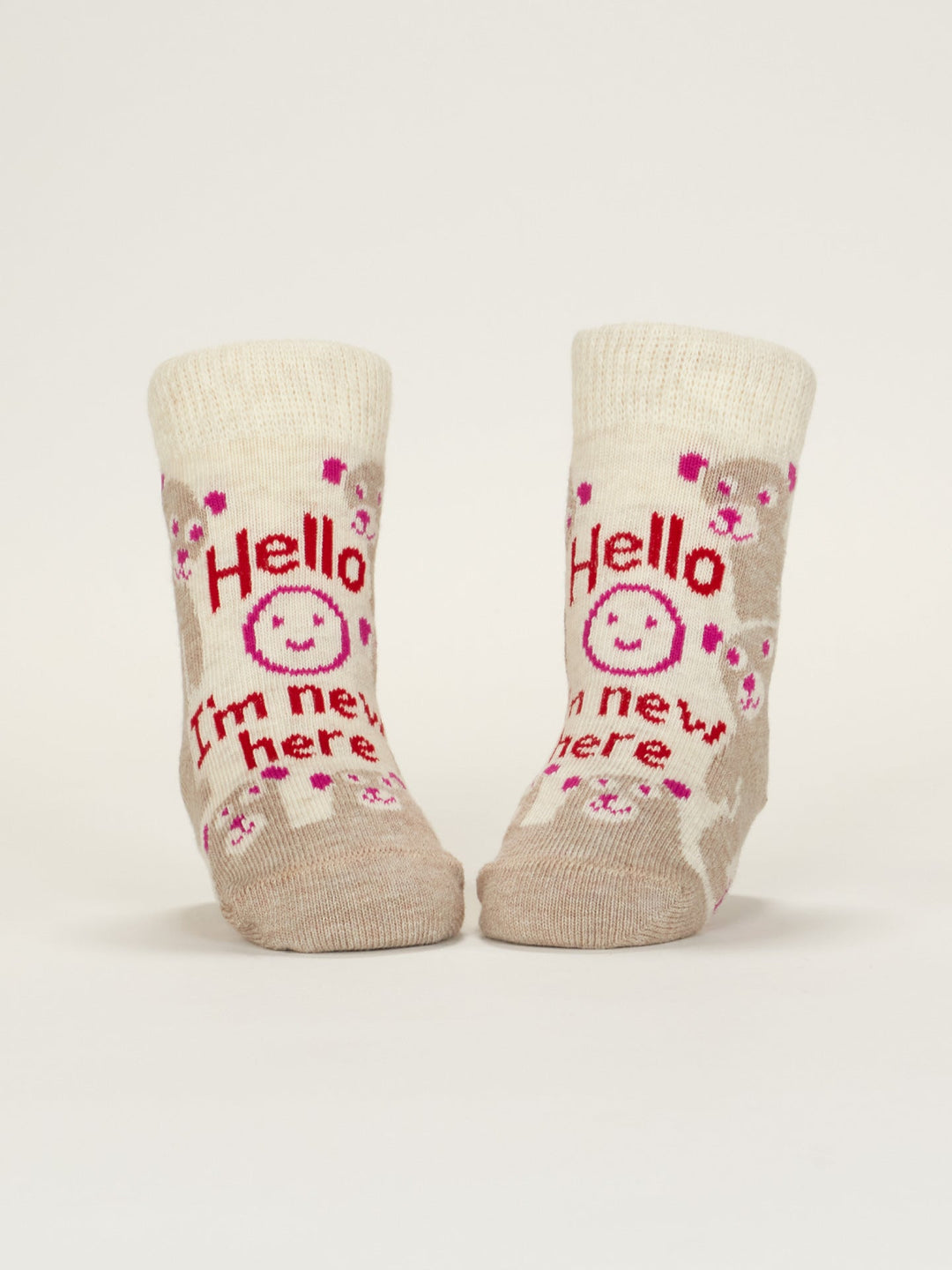 A pair of beige Blue Q baby socks featuring pink and brown animal faces, a smiling sun, and "Hello I&