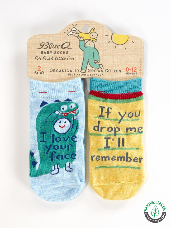 Blue Q’s “I Love Your Face/If You Drop Me I’ll Remember” baby socks set includes one blue pair with a dinosaur and one yellow pair with green trim. Made from OCS certified organic cotton, packaging features sun and baby designs.