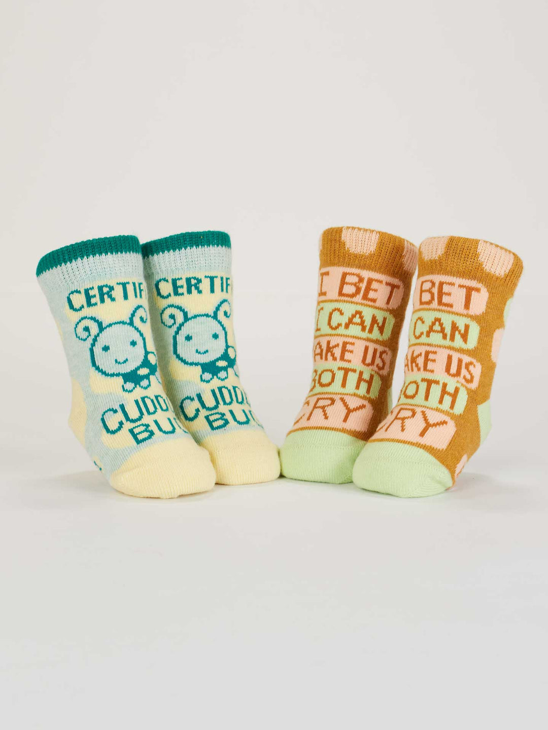 Blue Q Certified Cuddle Bug/I Bet I Can Make Us Both Cry baby socks feature two colorful organic cotton pairs—one blue/yellow with a bunny and one orange polka dot. Both are OCS Certified for peace of mind.