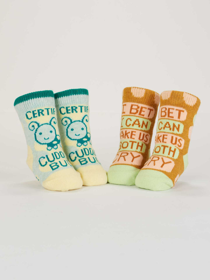 Blue Q Certified Cuddle Bug/I Bet I Can Make Us Both Cry baby socks feature two colorful organic cotton pairs—one blue/yellow with a bunny and one orange polka dot. Both are OCS Certified for peace of mind.