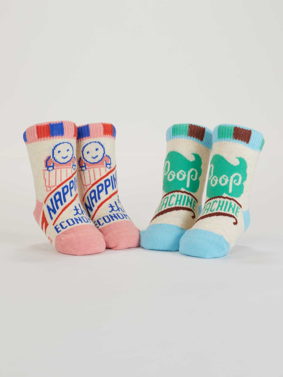 Blue Q Napping? In This Economy?/Poop Machine Baby Socks: two pairs—one pink with smiling faces and slogan, one blue/green with “Poop Machine” and a fun graphic—both in soft organic cotton for comfy naps.