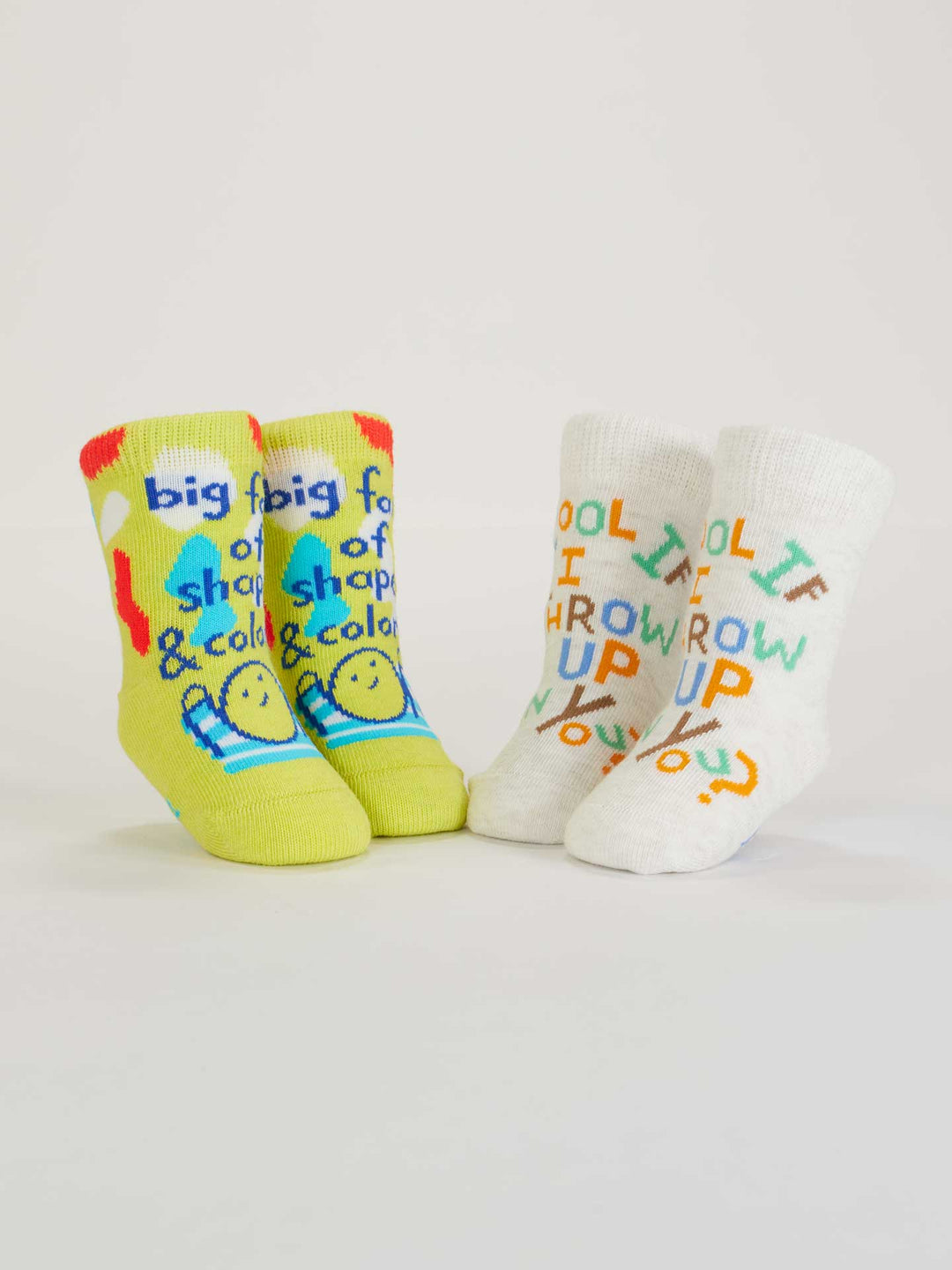 Two pairs of playful Blue Q baby socks: Big Fan Of Shapes &amp; Colors (yellow-green with smileys) and Cool If I Throw Up On You? (white with multicolored text). Made from organic cotton, perfect for adding fun to any outfit.