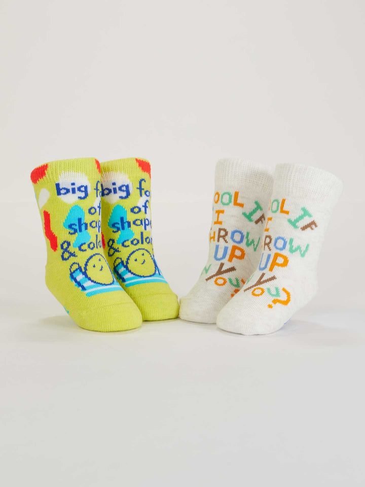 Two pairs of playful Blue Q baby socks: Big Fan Of Shapes &amp; Colors (yellow-green with smileys) and Cool If I Throw Up On You? (white with multicolored text). Made from organic cotton, perfect for adding fun to any outfit.