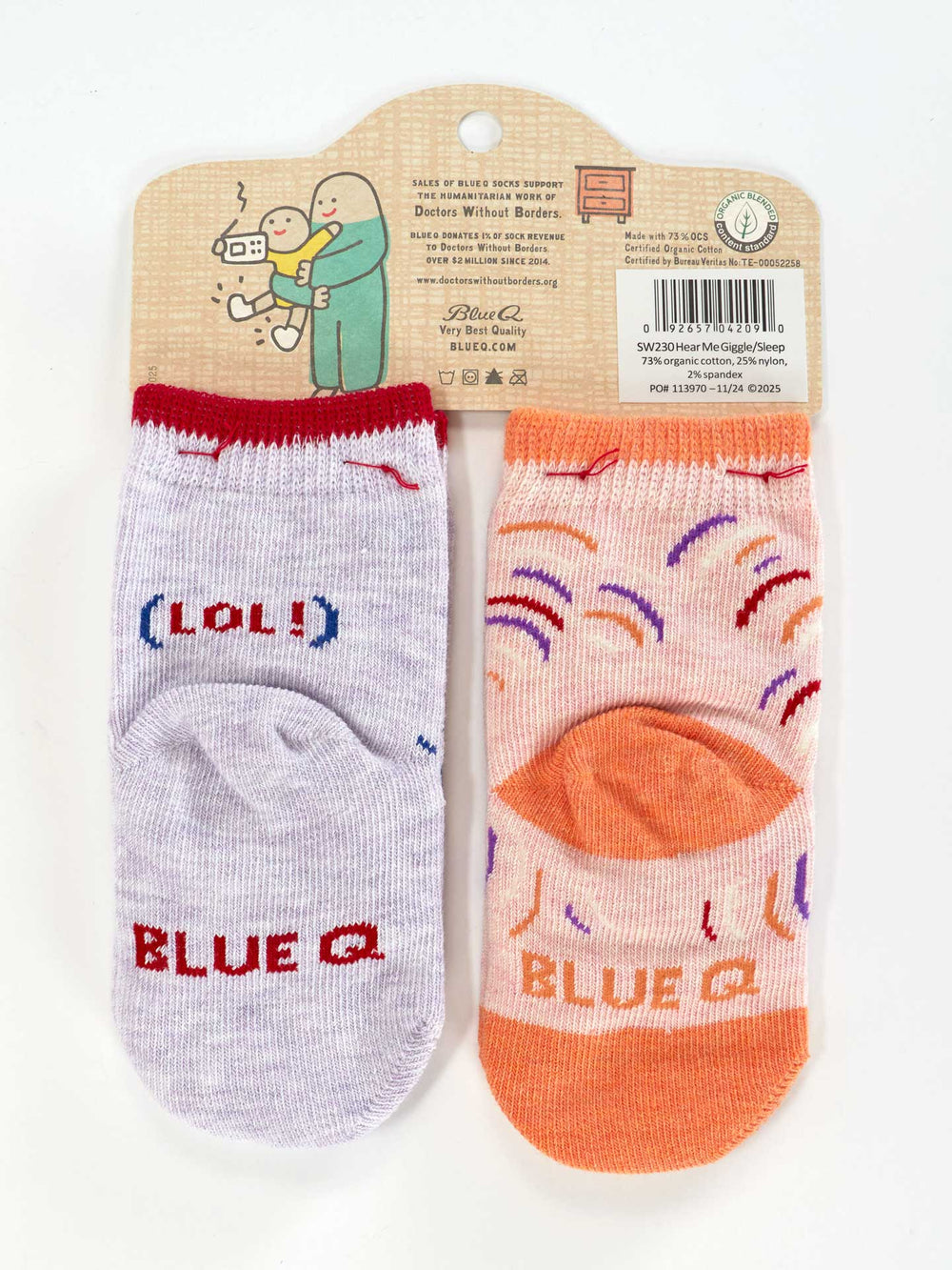Blue Q’s “Wait 'til You Hear Me Giggle./Just Sleep When I Sleep. Lol.” baby socks: one light purple sock with “(LOL)” and brand name, the other peach with sprinkles and a branded toe, both attached to a cardboard hanger.