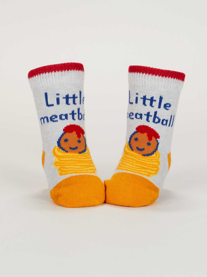 Blue Q’s “Little Meatball/ I Get Heavy Baby Socks” feature organic cotton, red trim, yellow toes and heels, a smiling meatball on spaghetti, and “Little meatball” in blue—perfect for your little one!.