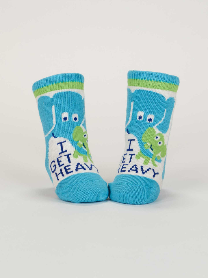Blue Q’s Little Meatball/ I Get Heavy Baby Socks are blue organic cotton socks for babies, featuring a cartoon elephant with a green dumbbell and "I GET HEAVY" text below the design.