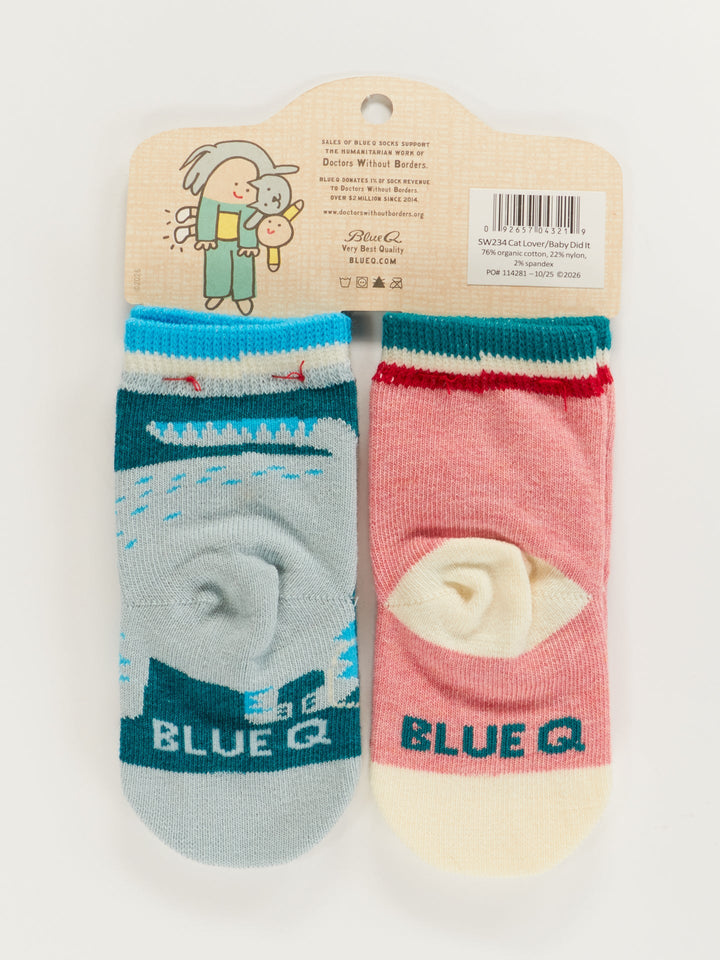 Cat Lover Jr./The Baby Did It. Baby Socks by Blue Q: a cute newborn sock set on a hanger card, featuring one blue sock with a whale and one pink with a cat, both with cream toes and heels and "BLUE Q" on the foot—perfect for little ones.