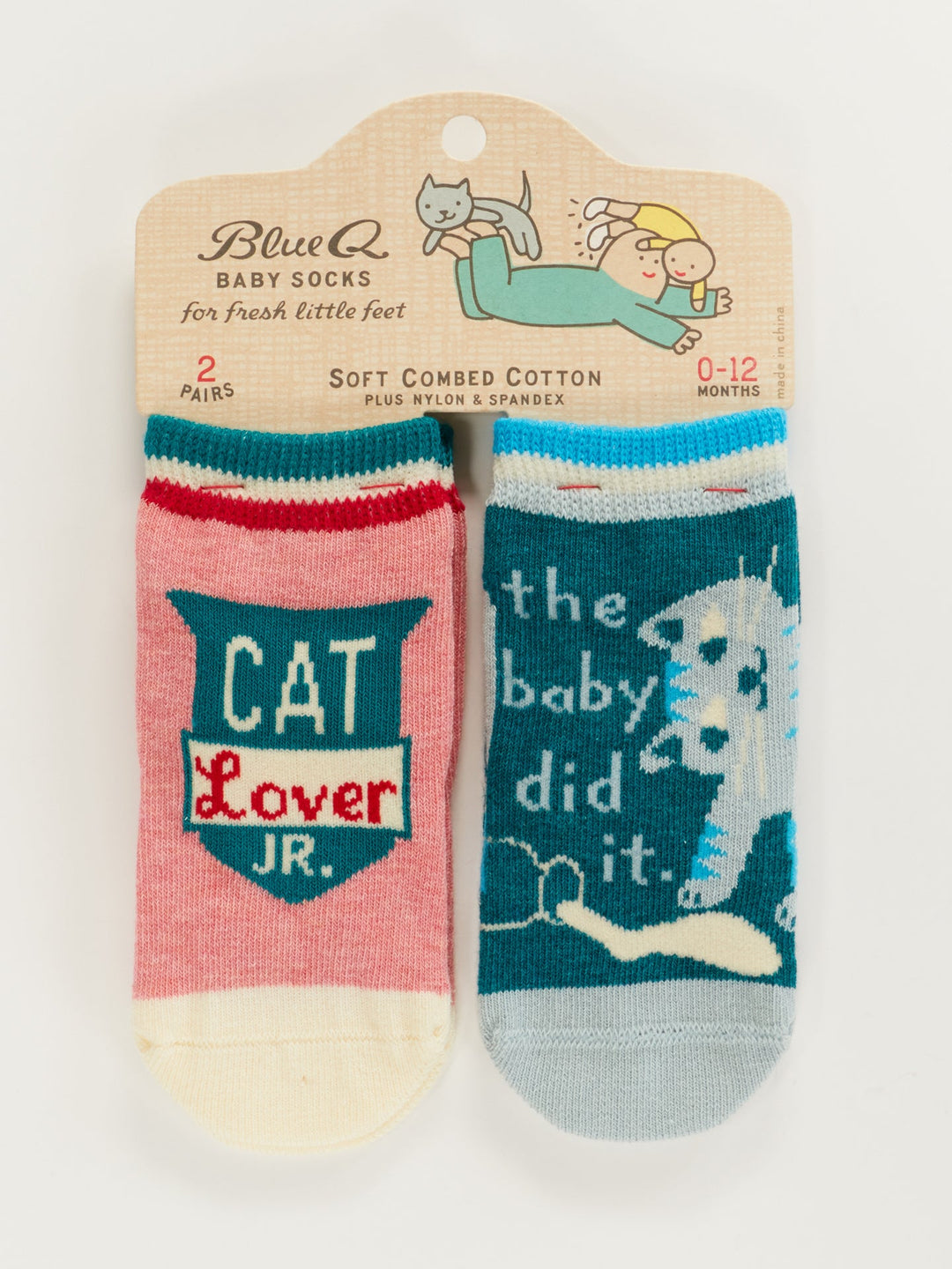 Two pairs of Blue Q baby socks—one pink and cream with "Cat Lover Jr.," the other blue with a cat and "The Baby Did It"—are shown in packaging featuring a cartoon baby chasing a cat. Product name: Cat Lover Jr./The Baby Did It. Baby Socks.