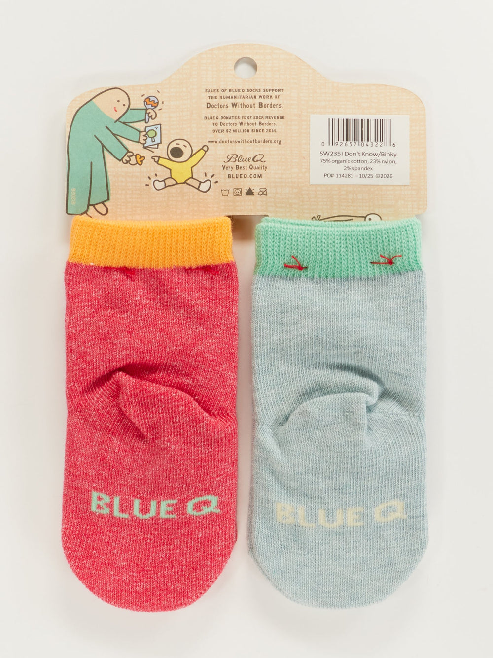 Blue Q "I Don't Know What I Want/Binky! Binky! Binky!" baby socks set (0–12 months) features two organic cotton mismatched socks on a hanger with a cartoon person and dog. One sock is red/orange, the other light blue/green, both marked BLUE Q.
