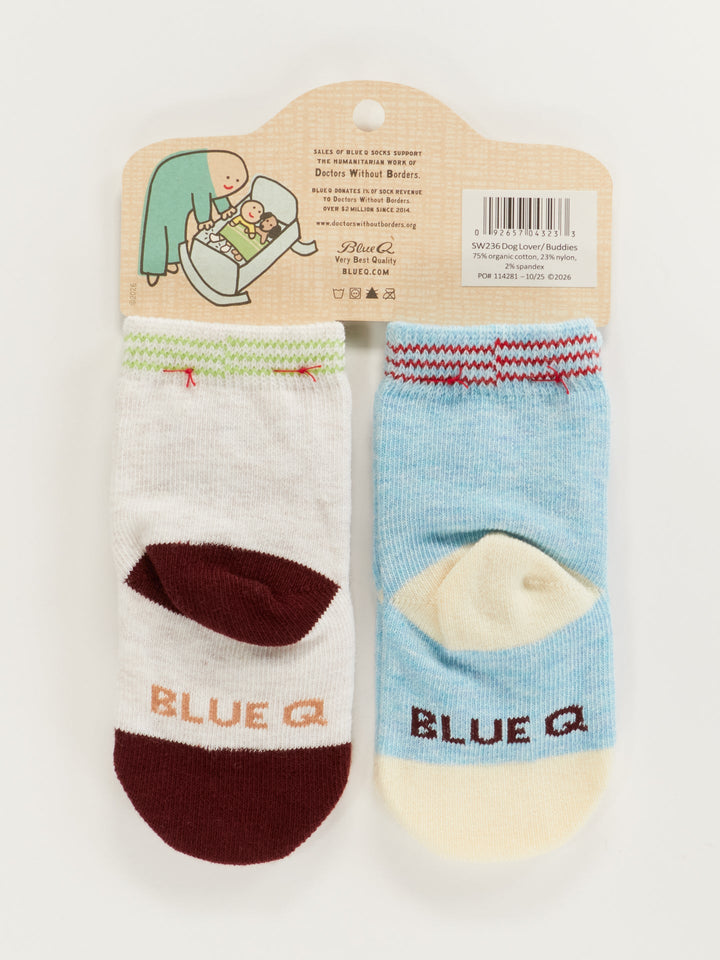 Blue Q Dog Lover Jr./Itty Bitty Buddies Baby Socks: Two pairs (0-12 months) on a cardboard hanger—one white with maroon, one blue with cream, both with "BLUE Q" on the toes. Packaging features a cute cartoon. Perfect baby gift!.