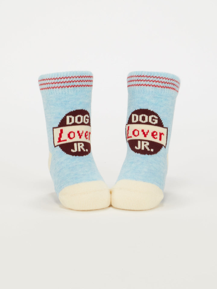 Blue Q Dog Lover Jr./Itty Bitty Buddies Baby Socks: Light blue organic cotton with cream toes and heels, featuring a red and black "DOG LOVER JR." design. Perfect for babies 0-12 months.