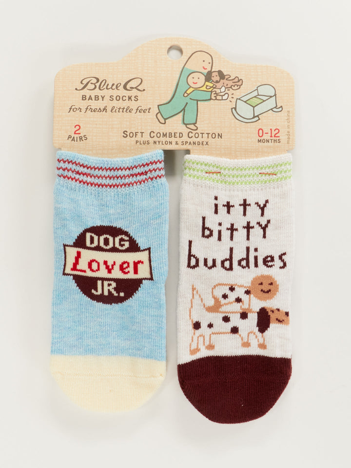 Blue Q Dog Lover Jr./Itty Bitty Buddies Baby Socks: set of 2 pairs for ages 0-12 months—one blue with "Dog Lover Jr." text, one white with cartoon dogs and "itty bitty buddies" design.