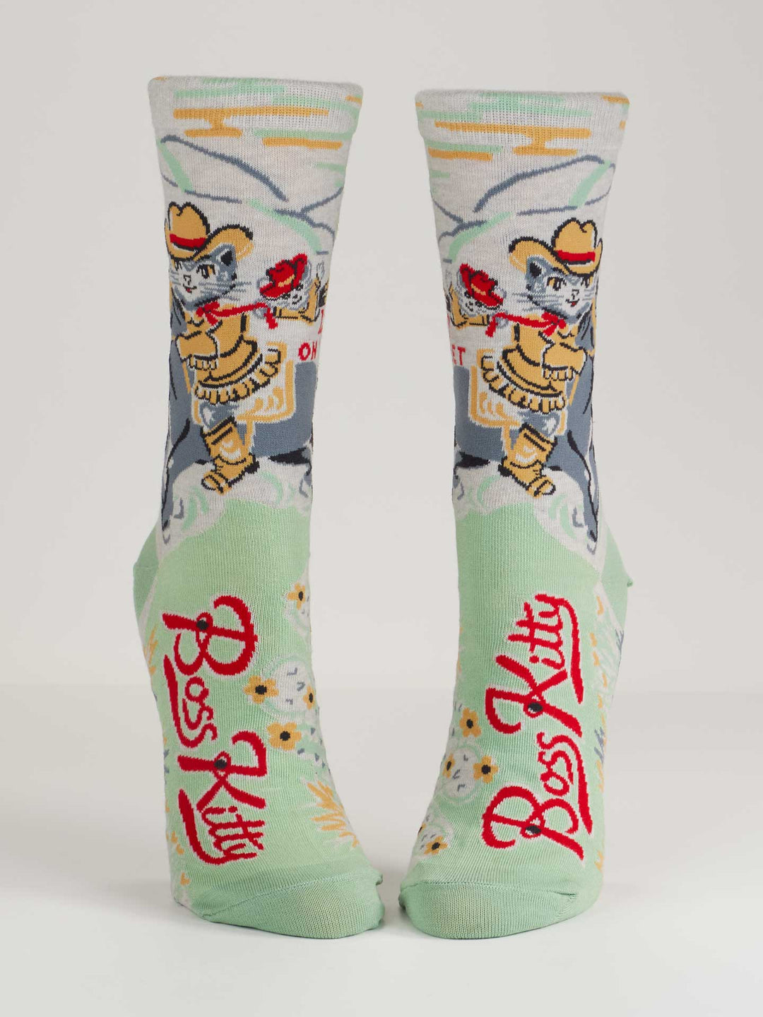 Blue Q’s Boss Kitty W-Crew Socks are light green combed cotton socks with a cowboy cat, lasso, red roses, and "Boss Kitty" in bold red—perfect for ruling your wild frontier.
