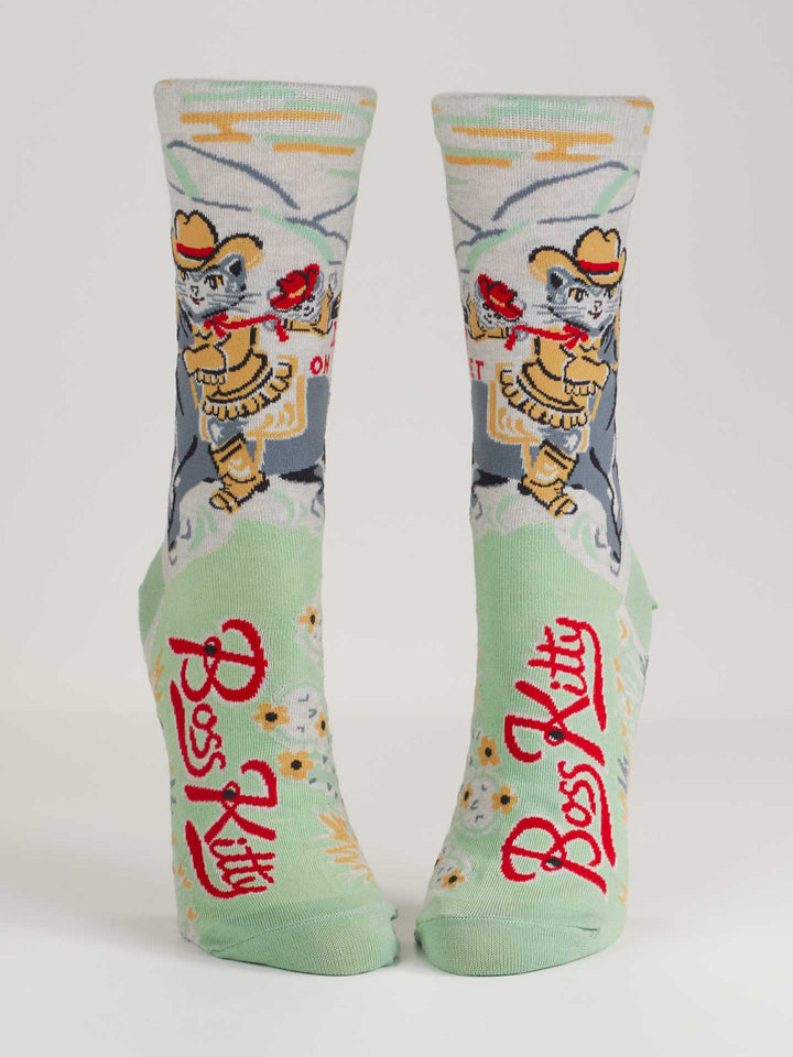 Blue Q’s Boss Kitty W-Crew Socks are light green combed cotton socks with a cowboy cat, lasso, red roses, and "Boss Kitty" in bold red—perfect for ruling your wild frontier.