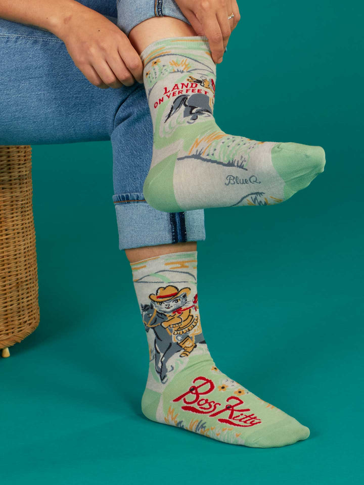 A person in rolled-up blue jeans sits on a woven stool, showing off Blue Q&