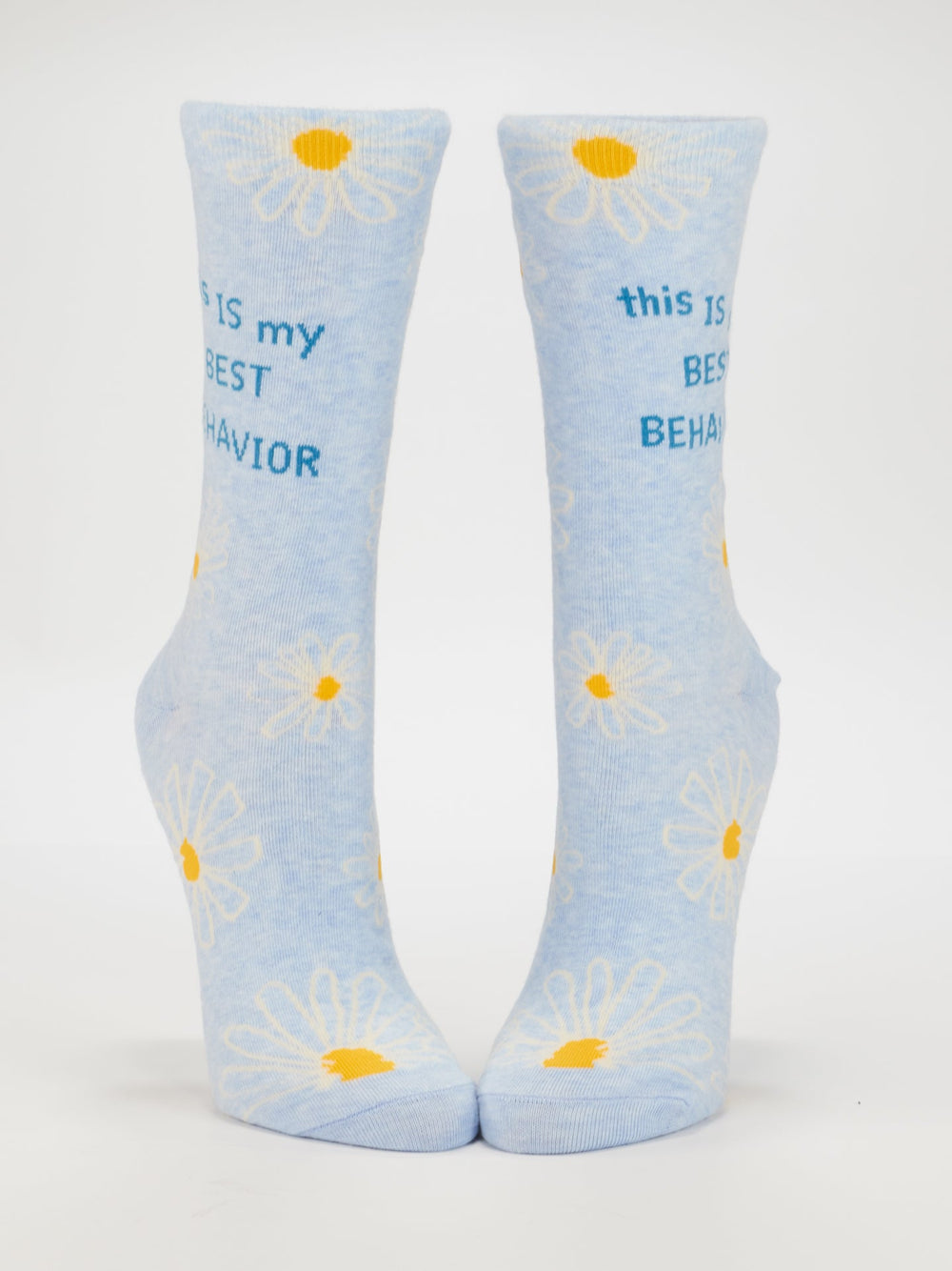 Blue Q’s This Is My Best Behavior W-Crew Socks feature light blue combed cotton, white and yellow daisies, and “this IS my BEST BEHAVIOR” in blue text. Fits women’s shoe size 5-10. Displayed upright on a white background.