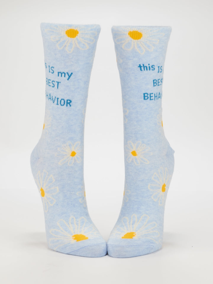 Blue Q’s This Is My Best Behavior W-Crew Socks feature light blue combed cotton, white and yellow daisies, and “this IS my BEST BEHAVIOR” in blue text. Fits women’s shoe size 5-10. Displayed upright on a white background.