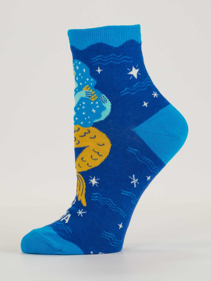 The Deep Sea Diva W-Ankle Socks by Blue Q are blue cotton socks with a colorful design of two mermaids—one blue, one yellow—among stars and waves, perfect for fans of unique women’s socks.
