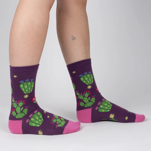 Women's cactus crew socks in purple with pink trim, worn side view showing blooming prickly pear cacti