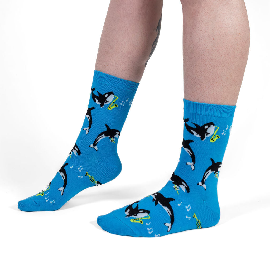 Orca-stra women's crew socks with orcas playing wind instruments, model side view