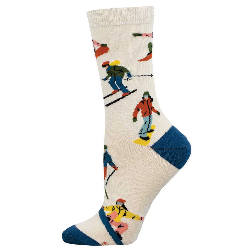 Women's snow day crew socks in cream with skiers and snowboarders, worn on foot