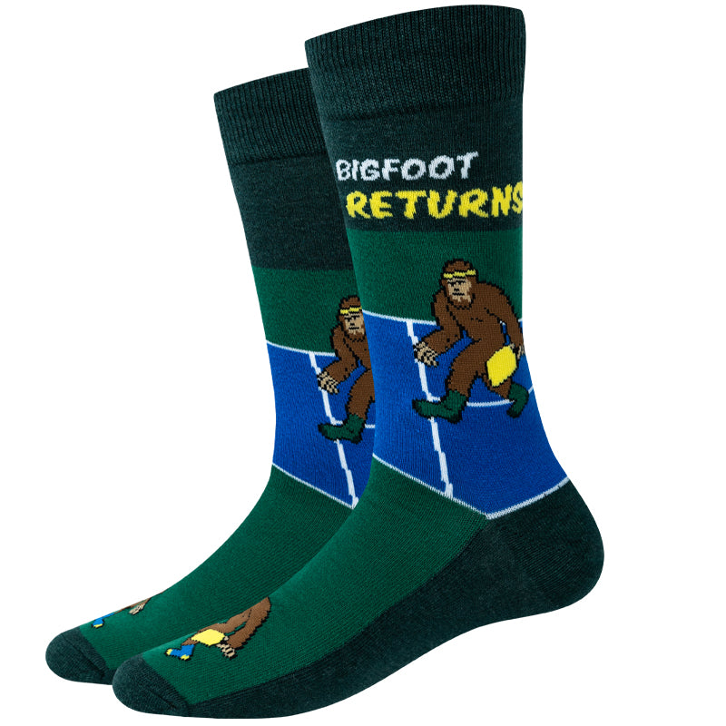 Unisex pickleball Bigfoot crew socks in dark green with Bigfoot on a blue court and "Bigfoot Returns" text, product shot of a pair