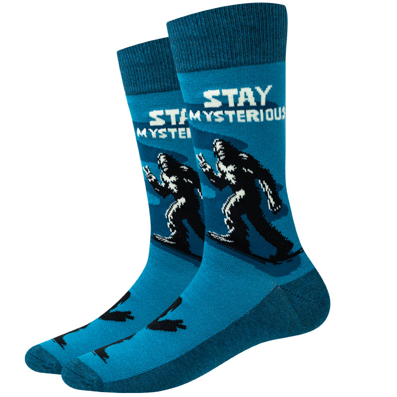 Unisex stay mysterious Bigfoot crew socks in teal with a Bigfoot silhouette flashing a peace sign, product shot of a pair