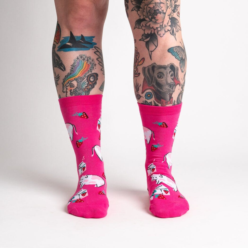Women's Strawberry Milk crew socks, worn front view on tattooed legs, pink dairy print