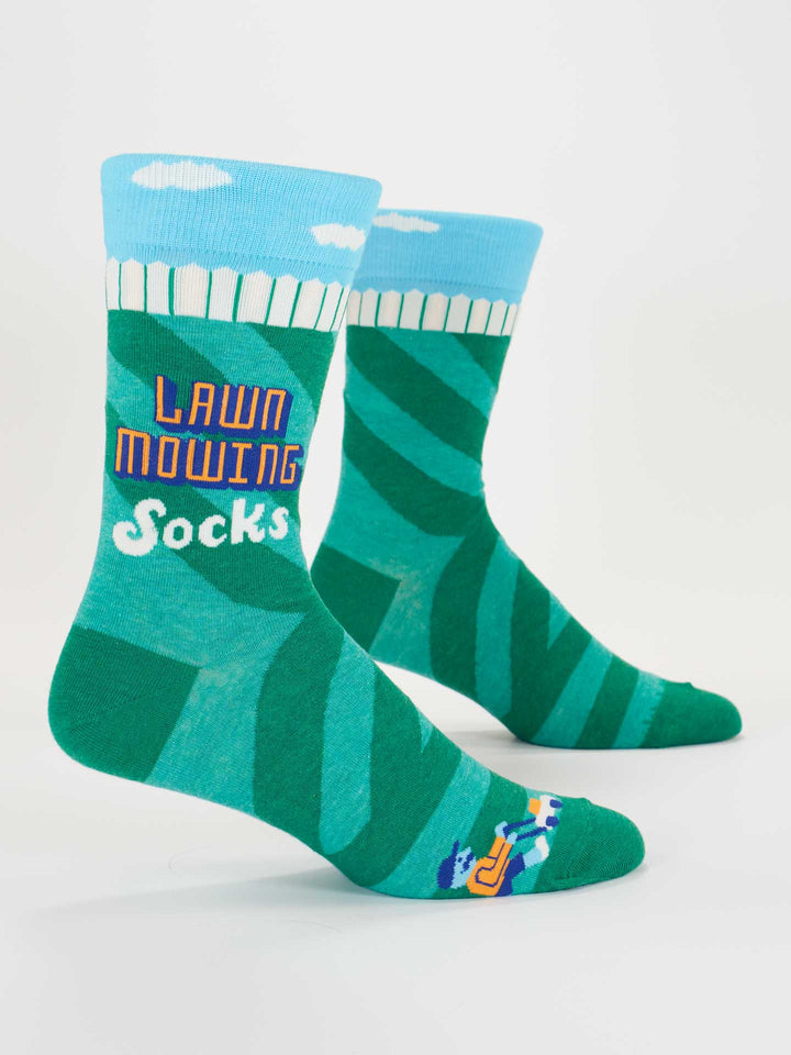 Blue Q’s Lawn Mowing Socks M-Crew feature green combed cotton with a lawn pattern, blue cloud tops, colorful “LAWN MOWING SOCKS” text, a small mower and stripes at the toes. Fits men’s shoe sizes.
