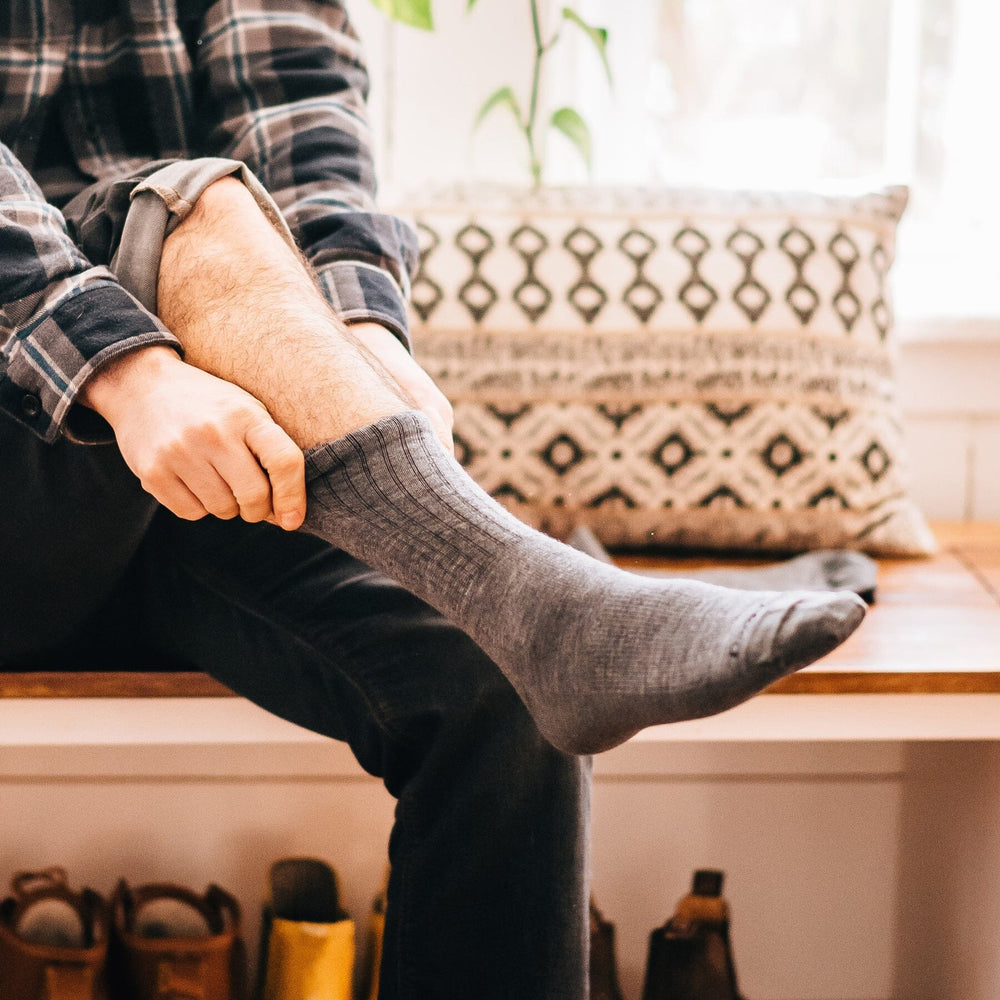 Man wearing gray ribbed crew socks, worn lifestyle shot indoors