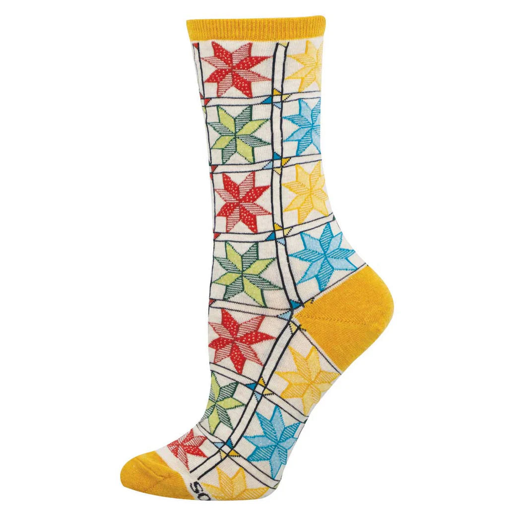 Women's quilting pattern crew socks laid flat, cream with colorful patchwork quilt stars and yellow heel and toe