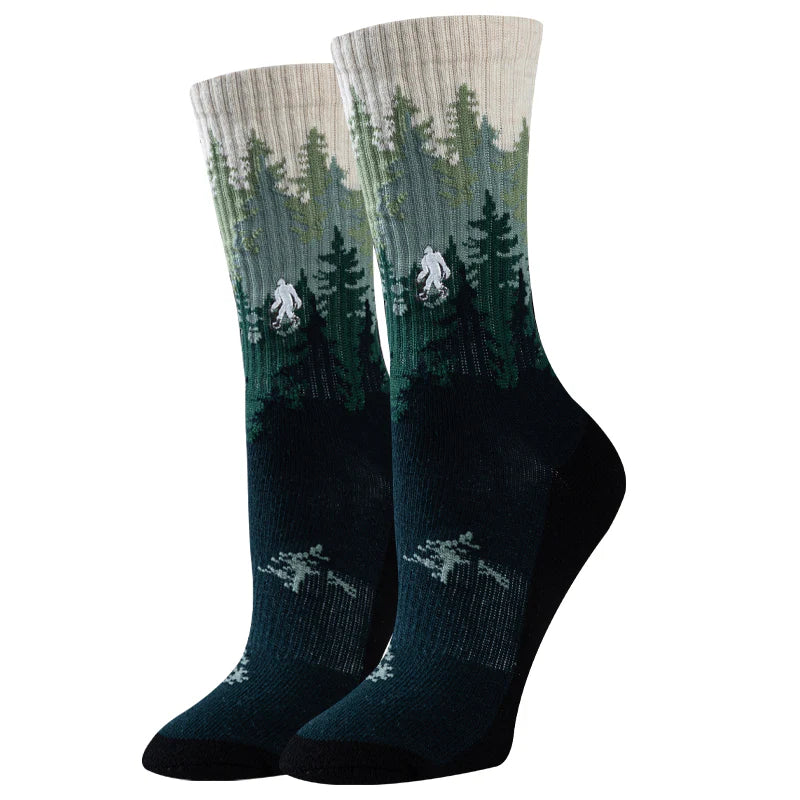 Women's forest crew socks with pine trees and Bigfoot, flat lay