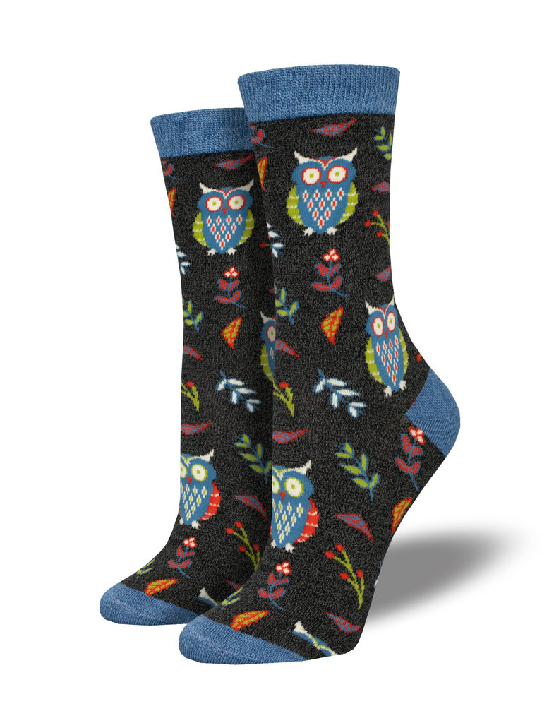 Pair of women's charcoal crew socks with blue and green owls, leaves, and flowers and denim-blue cuffs, heels, and toes