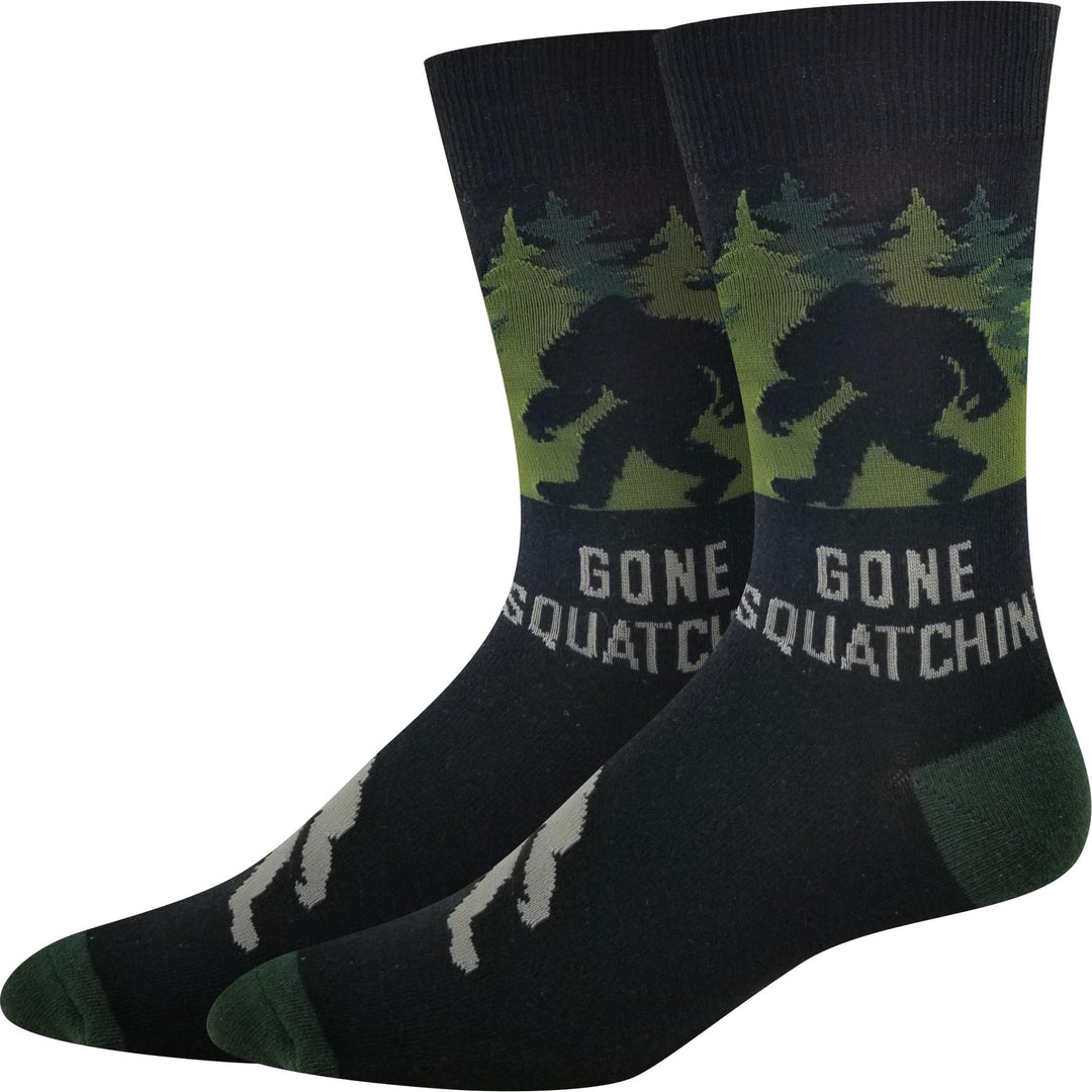 Pair of unisex crew socks with a green pine forest, Bigfoot silhouette, and Gone Squatchin' lettering